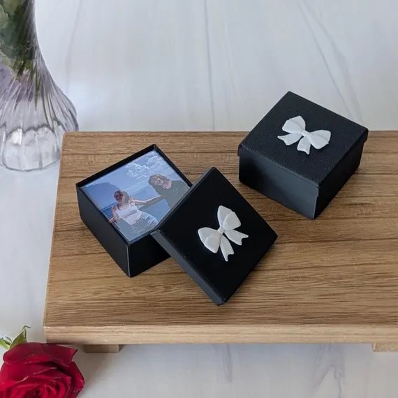 Elegant black gift boxes with white ribbons holding a custom photo magnet, ready for shipping to customers