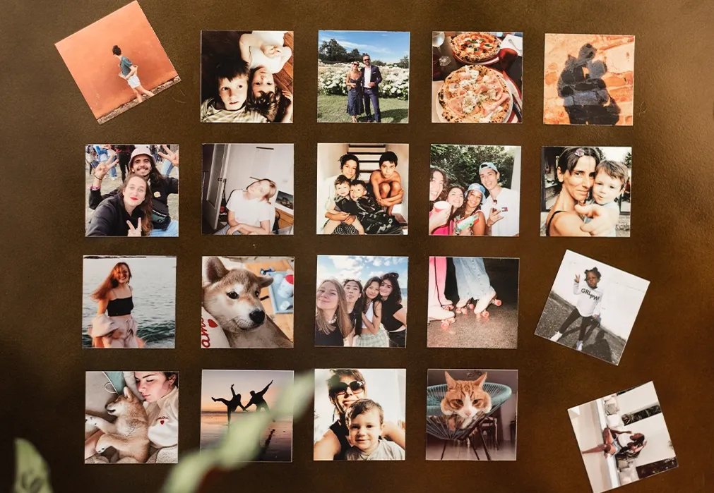 A grid of square custom photo magnets with family, travel, and pet photos arranged on a dark surface